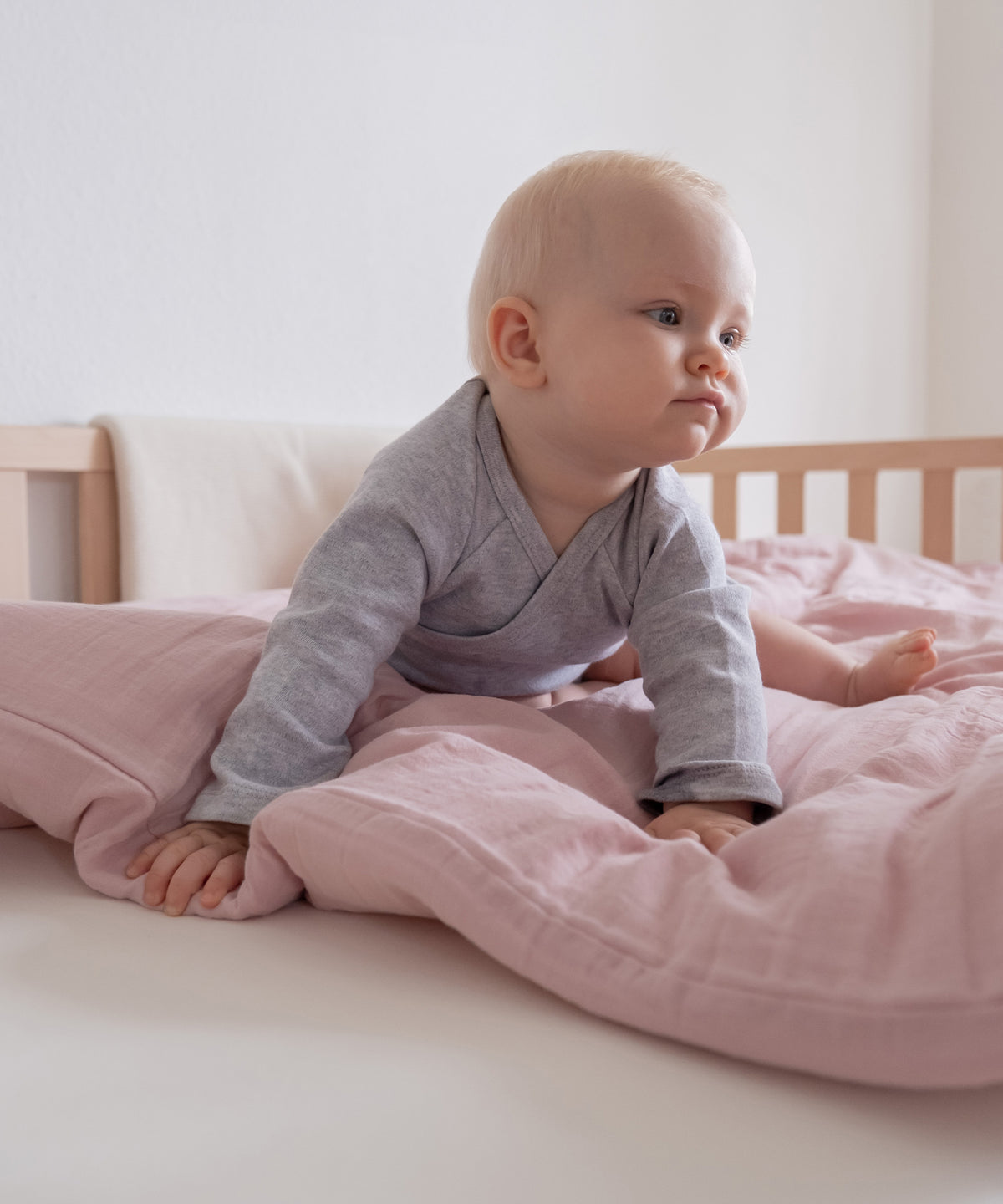 Baby sitzt auf einer Decke mit Bettwäsche.