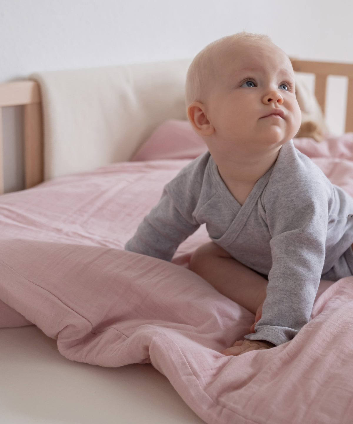 Baby sitzt auf der Bettwäsche.