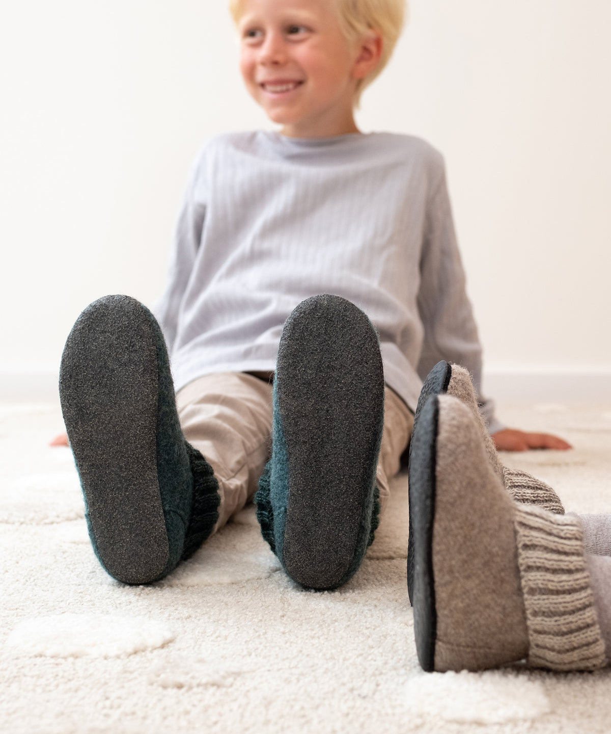 Kinder mit Hüttenschuhen für Kinder auf Teppich.