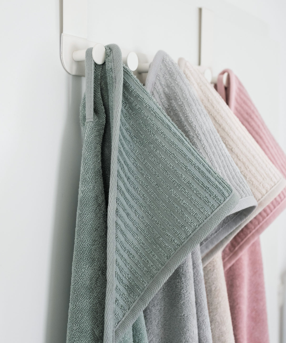 Kapuzenhandtücher in vier Farben hängen an Badezimmer-Garderobe.