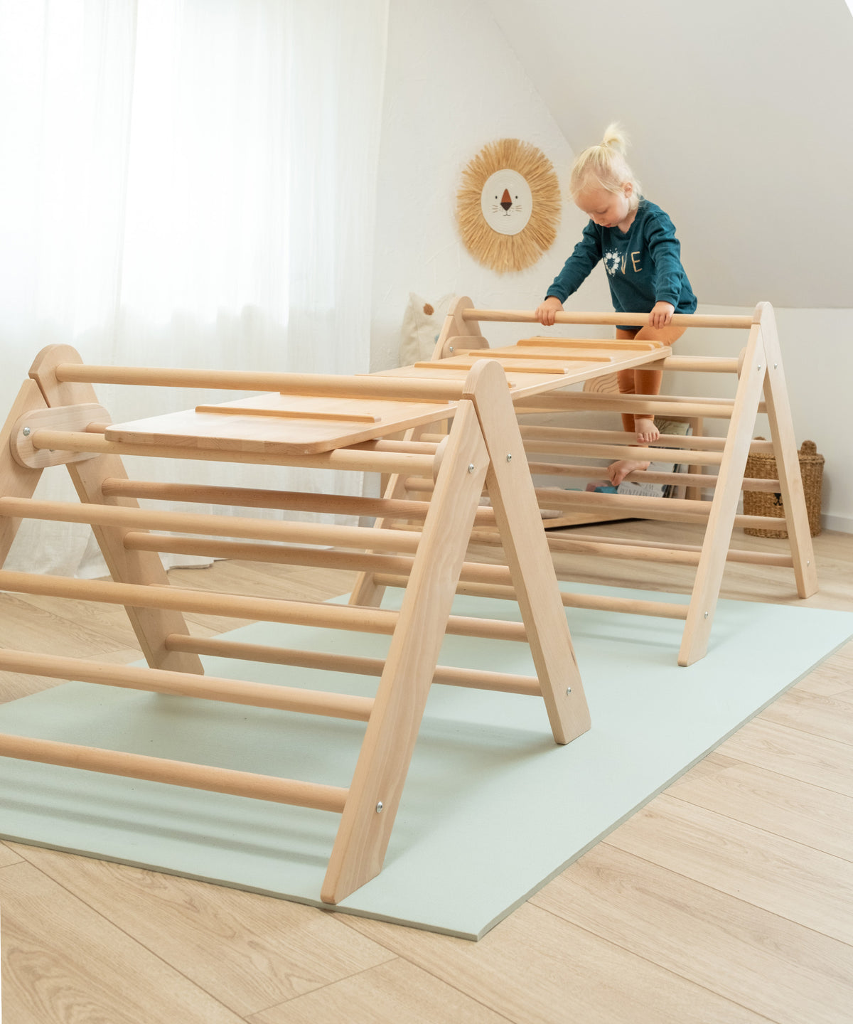 Zwei Kletterdreiecke wurden mit einem Rutschbrett verbunden. Kind klettert auf das Kletterdreieck.