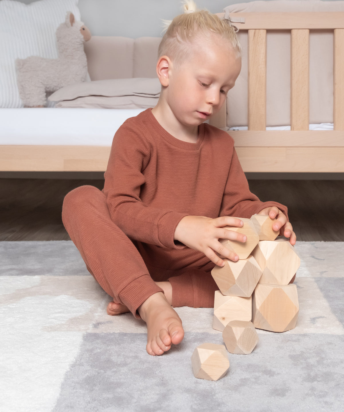 Junge mit Kinder Pyjama spielt mit Balanciersteinen.