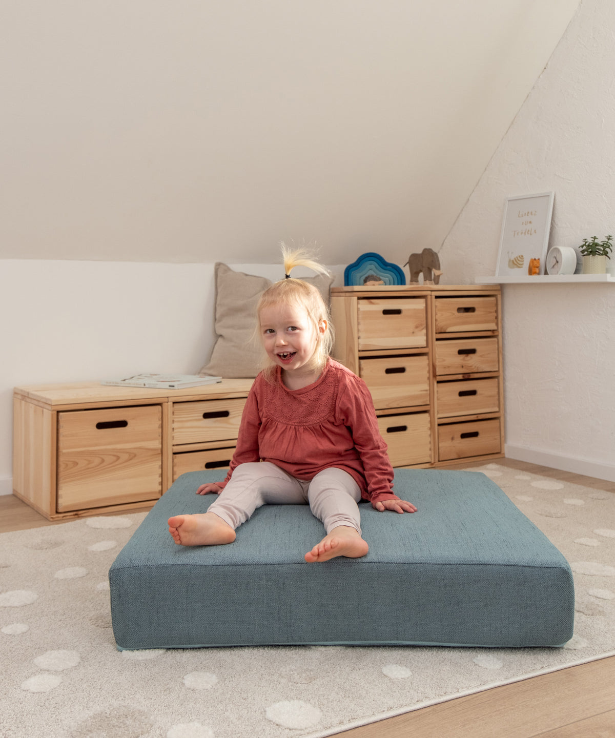 Kind sitzt auf Hüpfpolster in Kinderzimmer.